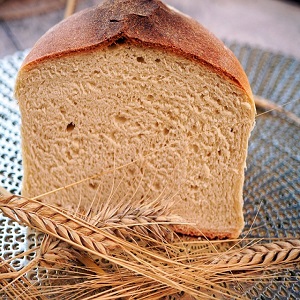 Main image for an article about barley bread: A fresh, golden loaf of barley bread is shown on a wooden table, surrounded by whole barley grains, highlighting its dense texture and health benefits. The image reflects the rich nutritional nature of barley bread and invites readers to discover its benefits in promoting health and supporting a healthy lifestyle.